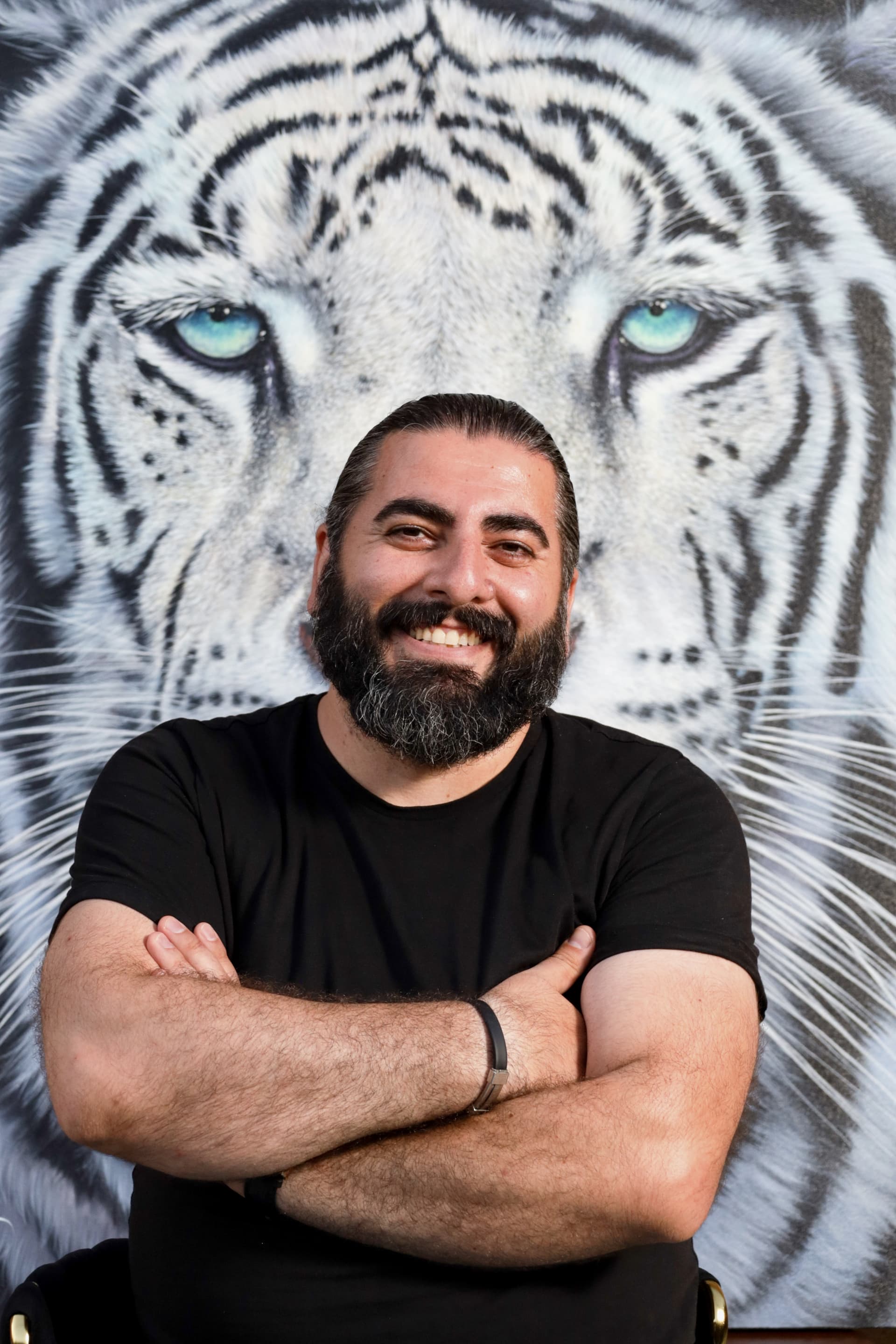 Portrait of Artak Hambardzoumyan with a hyperrealistic tiger artwork in the background